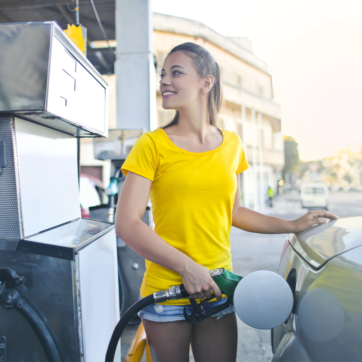 Young woman pumping gas into her car